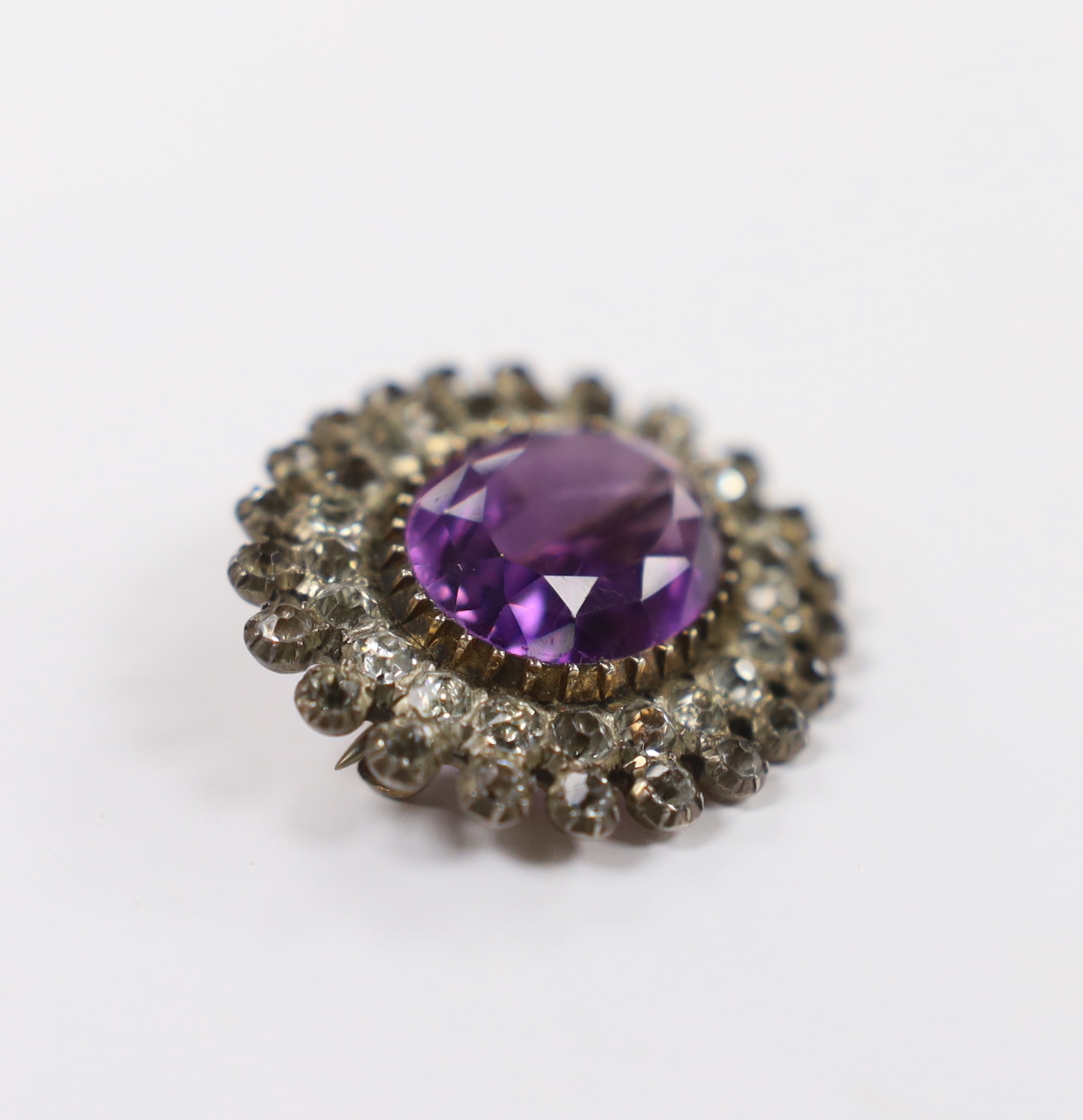 An early 20th century yellow and white metal, amethyst and paste set oval cluster brooch, 33mm.